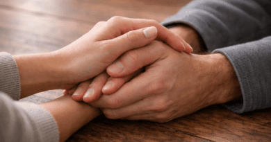 Hands clasped together on a table.