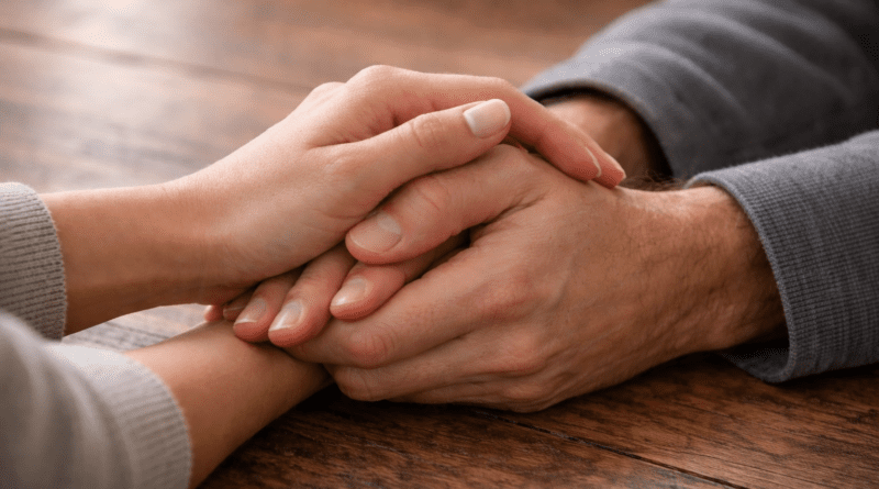 Hands clasped together on a table.