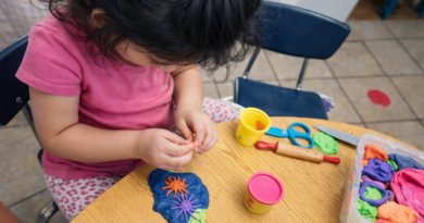 Child sitting at the table with play doh.