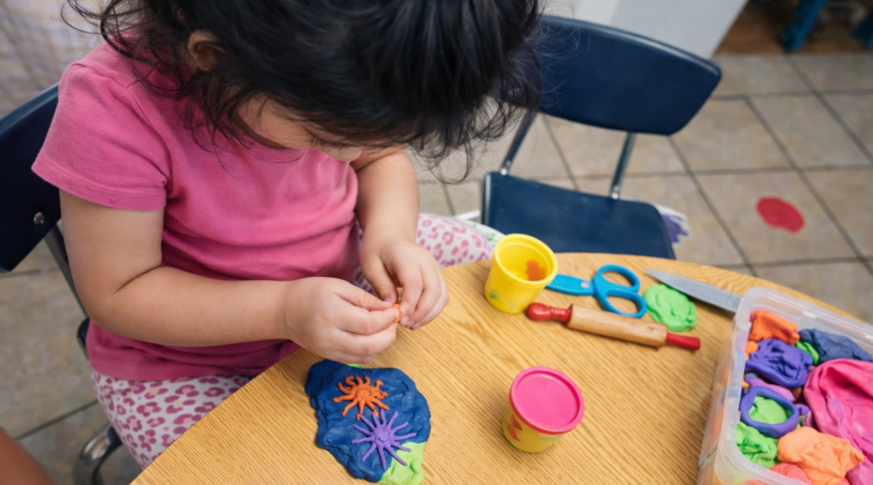 Child sitting at the table with play doh.